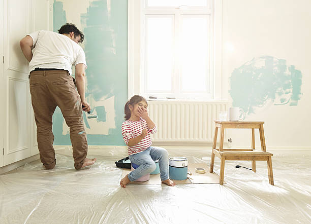 Jeune papa qui peint une chambre d'enfant avec sa fille