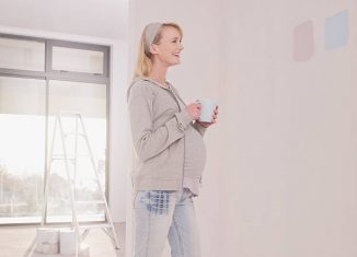 Femme enceinte qui essaye de choisir la couleur de la peinture de la chambre de son bébé