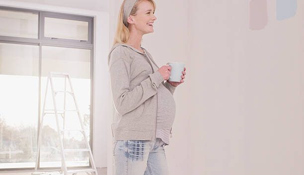 Femme enceinte qui essaye de choisir la couleur de la peinture de la chambre de son bébé