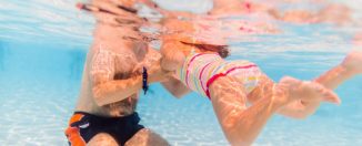 Jeune papa qui apprend à nager à sa fille dans une piscine