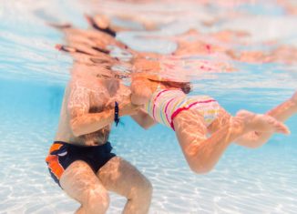 Jeune papa qui apprend à nager à sa fille dans une piscine