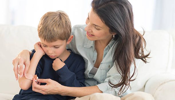 Maman qui met un pansement sur le bras de son fils qui s'est fait mal