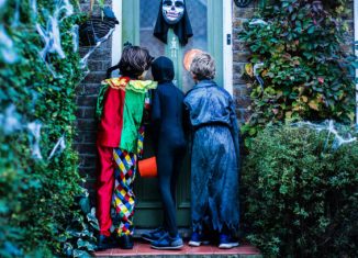 Trois enfants déguisés qui frappent à une porte à Halloween