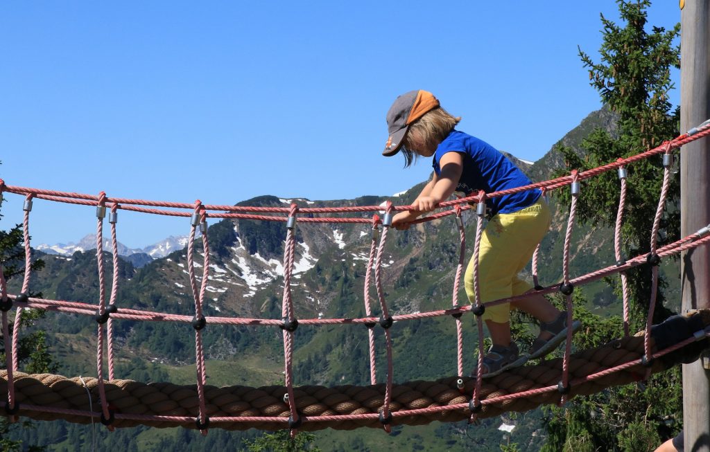 Enfant qui marche sur un pont suspendu à la montagne