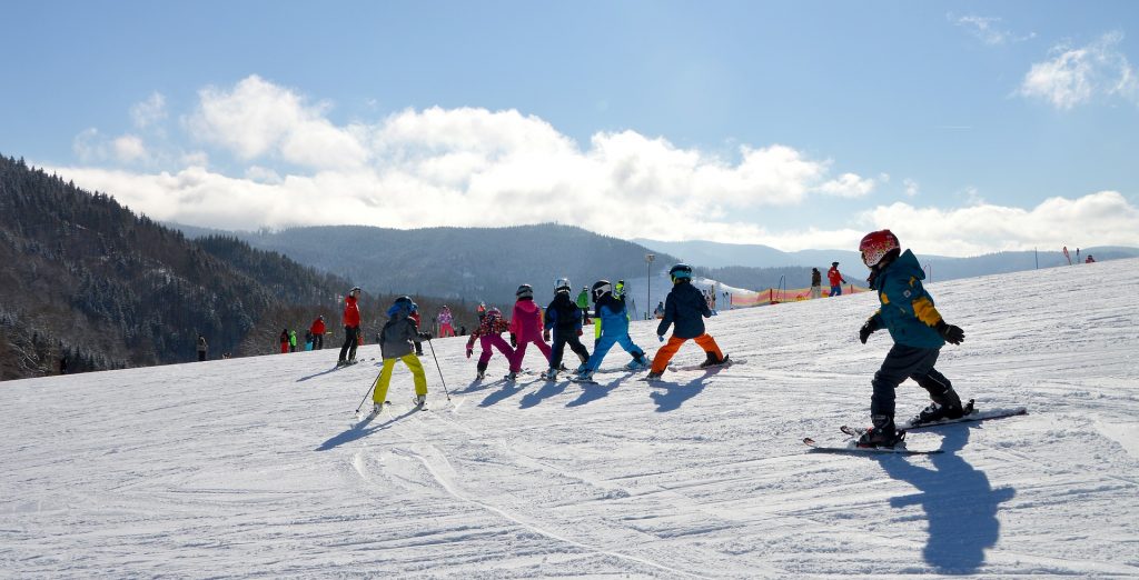 Groupe d'enfants qui font du ski à la montagne sous un ciel bleu